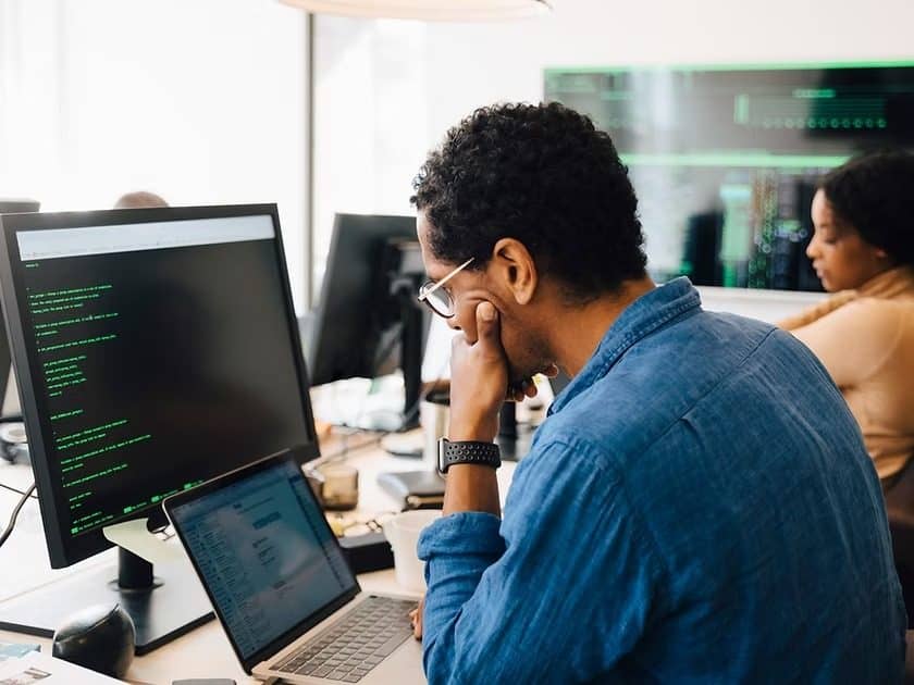 Expert reviewing code on several screens